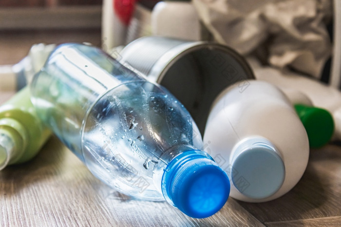 塑料瓶纸和金属罐是分散在的厨房地板上垃圾浪费塑料瓶纸和金属罐是分散在的厨房地板上