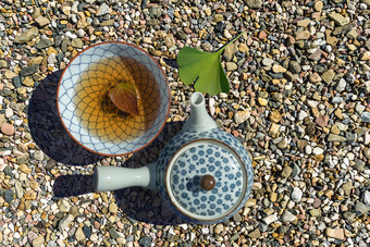 垂直视图日本填满茶杯与茶叶日本茶壶和银杏叶砾石床上