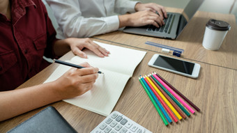 教学帮助技术概念女人年轻的老师导师与成人学生教室桌子上与论文移动PC电脑研究课程