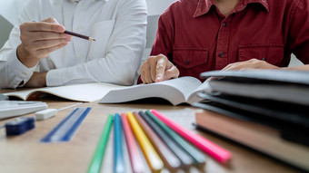 教学帮助技术概念女人年轻的老师导师与成人学生教室桌子上与论文移动PC电脑研究课程