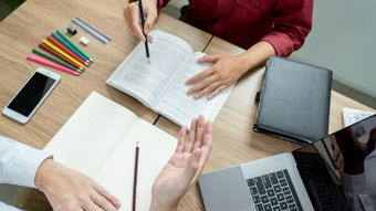 教学帮助技术概念女人年轻的老师导师与成人学生教室桌子上与论文移动PC电脑研究课程