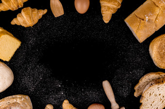 面包概念片面包面包羊角面包和饼面包安排圆的黑色的场景和洒面粉灰尘