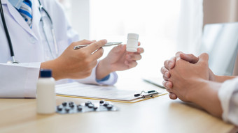 参观医生概念病人被建议如何取药丸的白色瓶为治疗