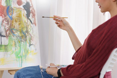 有创意的艺术概念年轻的亚洲女人坐工作室和持有画笔指出艺术作品