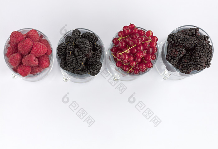 树莓大黑色的黑莓和红色的醋栗是倒成透明的玻璃杯为拿铁和站行光背景的图像高关键树莓大黑色的黑莓和红色的醋栗是位于清晰的玻璃光背景