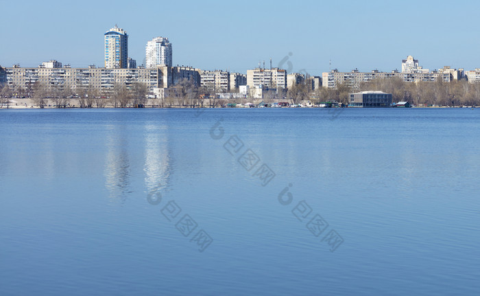 的平静表面的河反映了的蓝色的的春天天空对的背景的城市区深蓝色的的春天天空反映了的平静平滑度的河