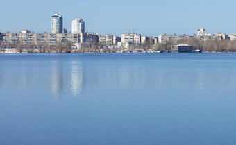 的平静表面的河反映了的蓝色的的春天天空对的背景的城市区深蓝色的的春天天空反映了的平静平滑度的河