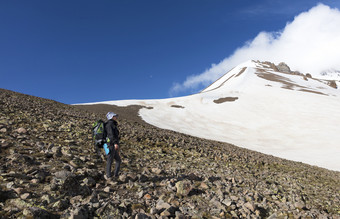 女人旅游与背包去徒步旅行雪山的旅游上升的山腰的白雪覆盖的峰会