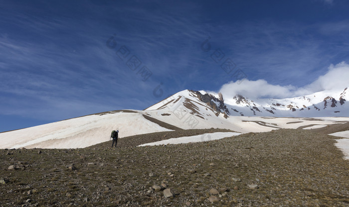 女人旅游与背包去徒步旅行雪山的旅游上升的山腰的白雪覆盖的峰会