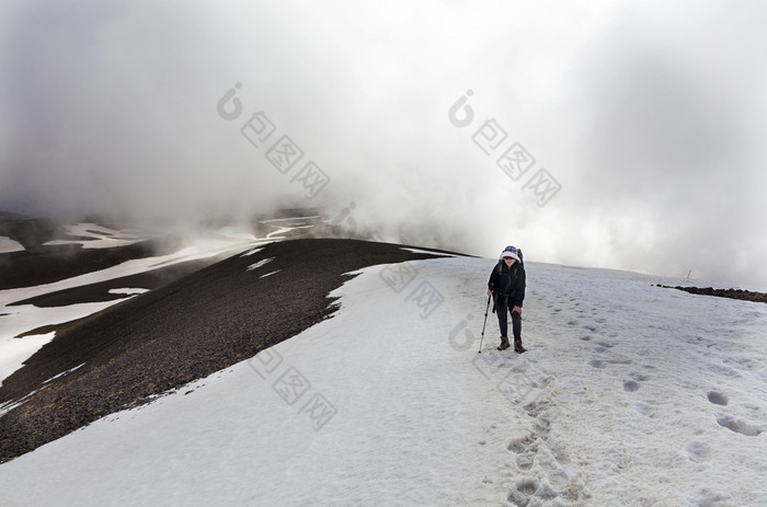 旅游女人与背包她的回来和跟踪坚持她的手去运动的白雪覆盖的山的旅游上升的山腰的白雪覆盖的峰会