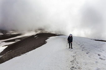 旅游女人与背包她的回来和跟踪坚持她的手去运动的白雪覆盖的山的旅游上升的山腰的白雪覆盖的<strong>峰会</strong>