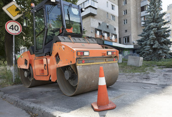 橙色路锥保护的工作区域为重振动压实机城市街橙色路锥保护重轮压实机沿着的边缘的城市街路