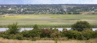 风景优美的视图从的相反银行的河村哪一个位于沿着的河与水梅多斯农村景观俯瞰的河与水梅多斯和农村房子