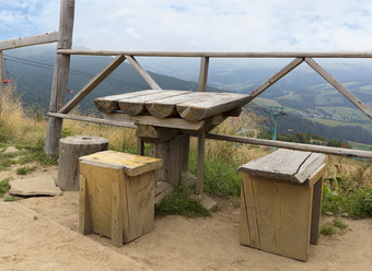 喀尔巴阡山老木天气表格和三个粗糙的简易椅子为喘息的机会前的山滑雪电梯的背景山景观简易休息区的形式粗糙的木表格和椅子前山的喀尔巴阡山