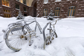 两个自行车成人和孩子链接的计数器外覆盖与雪在的雪两个自行车链接架外是覆盖雪在降雪