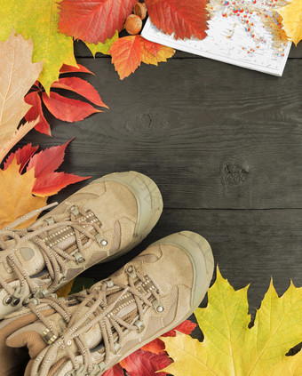 明亮的秋天叶子跟踪靴子和地图框架的黑色的老木表面与复制空间秋天叶子跟踪靴子和地图黑色的背景老树