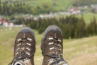 山跟踪靴子特写镜头后长长途跋涉通过的山模糊绿色背景的谷的夏天山山徒步旅行靴子特写镜头后长旅程通过的山