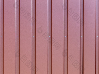 红褐色金属栅栏使波纹钢表与垂直指南和金属铆钉的中间波纹红褐色铁表背景关闭红褐色波纹钢表与垂直指南