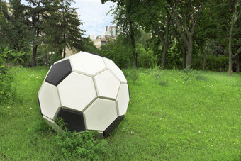 金属程式化的足球球绿色草坪上清算在的城市公园金属程式化的足球球绿色草坪上