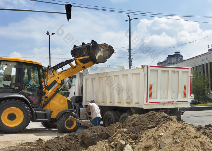 橙色机动拖拉机收集和加载建设碎片白色卡车可调动的建设拖拉机加载建筑碎片成卡车
