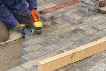 的<strong>工人</strong>躺的铺平道路板与特殊的锤子水准<strong>测量</strong>根据的水平的张拉线程铺平道路的瓷砖的人行道上的<strong>工人</strong>躺的瓷砖调整的线程