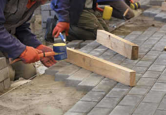 的<strong>工人</strong>躺的铺平道路板与特殊的锤子水准<strong>测量</strong>根据的水平的张拉线程铺平道路的瓷砖的人行道上的<strong>工人</strong>躺的瓷砖调整的线程