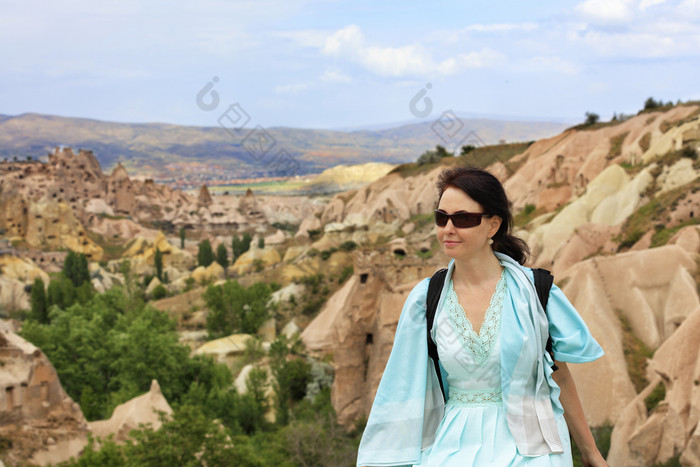 肖像年轻的美丽的女人太阳镜她的脸绿松石衣服和背包她的肩膀对的模糊景观山洞穴的山谷和峡谷卡帕多西亚肖像年轻的美丽的女人绿松石衣服对的背景模糊景观山山谷和峡谷卡帕多西亚