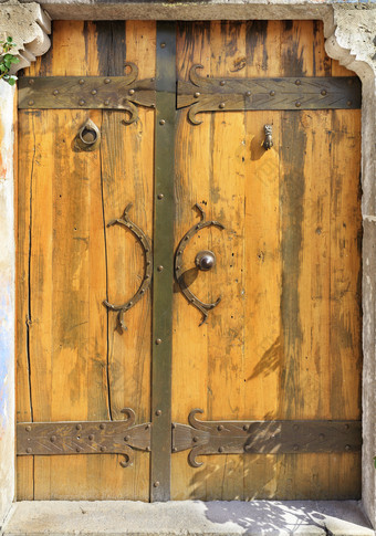 古董巨大的木门与造成处理铆钉和闩照亮明亮的阳光古董古董木门与伪造的处理铆钉和横档