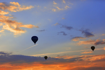 轮廓气球提高游客成的蓝色的天空以上的激烈的红色的云的早期早....对的背景飞机飞行高的天空轮廓气球的背景的早....天空与激烈的红色的云