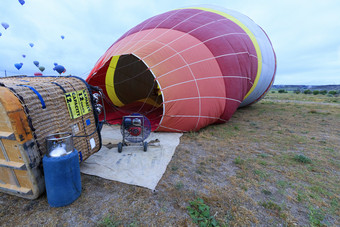 人膨胀气球与气体火炬和大容量汽油工业风扇倾斜的运输篮子的一边的过程膨胀气球与汽油风扇和气体燃烧器
