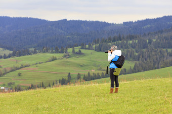 年轻的女孩摄影师芽的景观的喀尔巴阡山脉的山坡上新鲜的春天早....摄影师照片的景观的喀尔巴阡山脉的山坡上