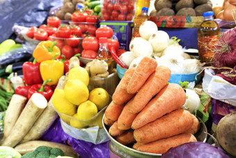的蔬菜市场销售许多不同的蔬菜这样的胡萝卜西红柿洋葱甜菜土豆欧芹根防风草茄子和柠檬和向日葵石油胡萝卜西红柿洋葱辣椒和其他蔬菜根蔬菜和柠檬向日葵石油是出售的市场货架上