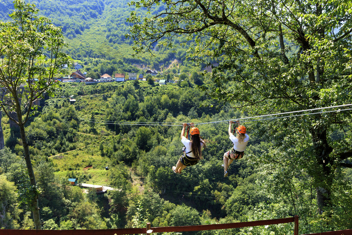 女孩的电缆车是发送通过的山和的森林通过的谷的河头饰黑山共和国游客交叉的长路径通过的山和森林在的河头饰电缆车