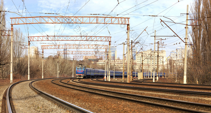 视图的移动铁路乘客火车蓝色的对的背景的城市景观乘客火车汽车的火车骑的铁路跟踪的背景的城市景观
