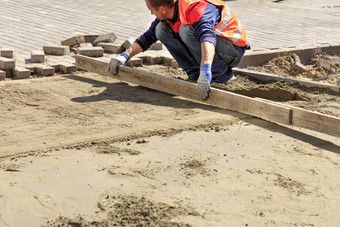 的人行道上工人对齐的沙子平台与木董事会准备的基金会为铺设铺平道路板工人对齐的沙子基地与木董事会为铺设铺平道路板的人行道上