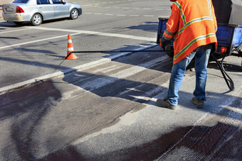 服务路维护工人喷雾的沥青混合物到的清洗区域为更好的附着力的新沥青的工人喷雾沥青的沥青表面部分修复的沥青路