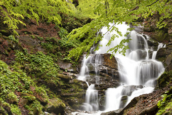 的快速流水瀑布大幅从的高度的喀尔巴阡山脉的山对的背景的周围绿色春天树叶强大的瀑布的山河喀尔巴阡山乌克兰