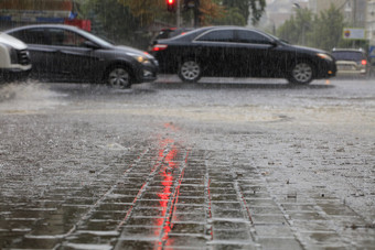 暴雨雨的路和的<strong>人行道</strong>上倒通过汽车照亮红色的交通光重雨的<strong>人行道</strong>上和沥青路照亮红色的交通光