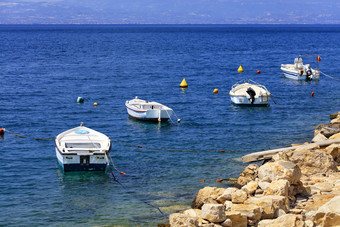 汽艇和船停泊从的岩石海岸的爱奥尼亚海对的背景的蓝色的哥林多湾汽艇和船是锚定沿着的岩石海岸的爱奥尼亚海