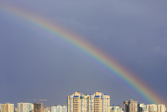 明亮的彩虹的天空以上城市房子后雷雨彩虹的天空以上的城市后雷雨