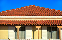 倾斜的光棕色（的）粘土瓷砖屋顶农村传统的单层房子南部希腊覆盖与棕色（的）瓷砖对蓝色的天空倾斜的光棕色（的）粘土平铺的屋顶农村传统的单层房子南部希腊点它的峰蓝色的天空