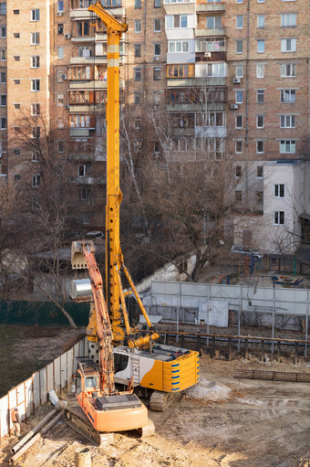 重建设设备挖掘机和高强大的起重机钻孔的地面为铺设混凝土桩的基金会的未来首页垂直图像与复制空间重履带式建设设备作品坚固建设网站在住宅建筑城市街