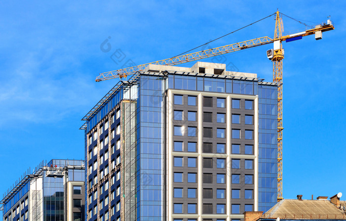 的建设现代住宅混凝土建筑与玻璃外观塔起重机使用的老住宅区域的城市是更新图像与复制空间玻璃外观蓝色的天空起重机附近现代混凝土建筑下建设改造老区