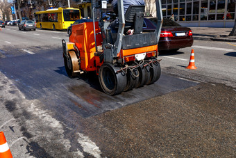 重橙色振动辊契约和水平部分路城市街坚固与交通视锥细胞图像与复制空间振动橙色路辊维修的路部分城市街