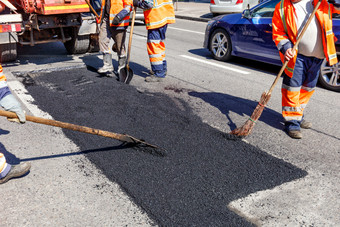工作集团路工人倒新鲜的沥青指定的部分的路和水平修复的巷道的工作团队维修的选择区域的车道