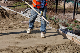 工人水平的<strong>基金</strong>会与沙子和铲下木水平为铺设铺平道路板对的背景的工作场所和准备为工作工人与铲穿沙子水平的<strong>基金</strong>会下的铺平道路板