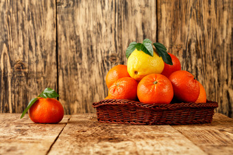 新鲜的柑橘类水果橘子和柠檬与绿色叶子柳条篮子和老木表格木背景复制空间橘子和柠檬柳条篮子和老木表格
