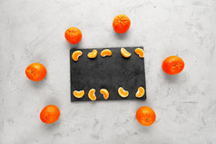 块橘子明亮的和多汁的谎言灰色的板岩包围整个橙色橘子位于灰色的混凝土背景复制空间明亮的和多汁的片普通话谎言灰色的板岩位于灰色的混凝土背景和包围整个橘子