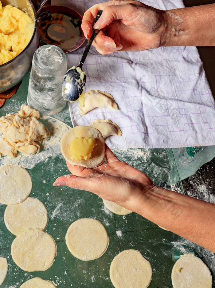 女人使用勺子与她的手造型饺子与土豆乌克兰国家厨房特写镜头女人使用勺子造型饺子与土豆乌克兰国家厨房