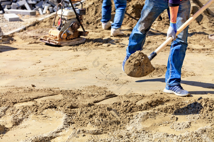 工人水平的基金会与沙子和铲下木水平为铺设铺平道路板对的背景的工作场所和准备为工作复制空间工人铲子沙子的工作区域